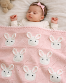 Baby lying on a pink blanket with bunny patterns, wearing a pink headband.