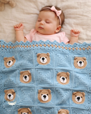 Baby sleeping under a blue crocheted blanket with bear faces, wearing a pink outfit and headband.