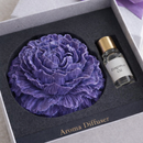 Gift set with purple aroma diffuser and oil bottle in a box with a purple ribbon.